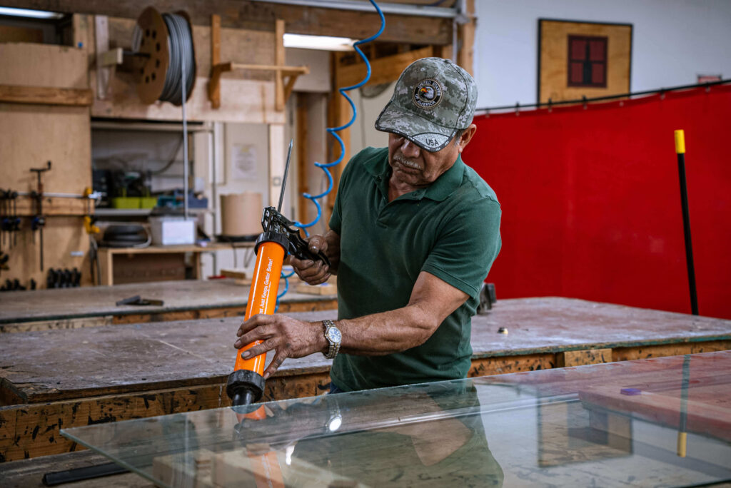 Craftsman applying structural silicone to a glass panel for bronze window glazing