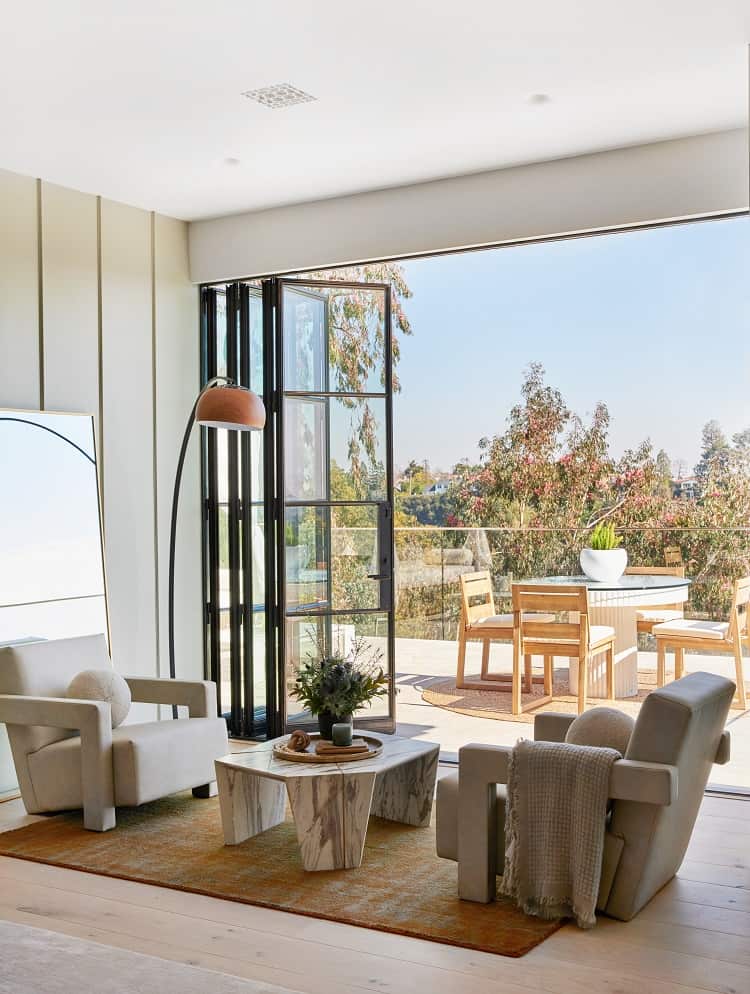 Modern interior with open bronze-framed folding doors connecting to an outdoor dining area