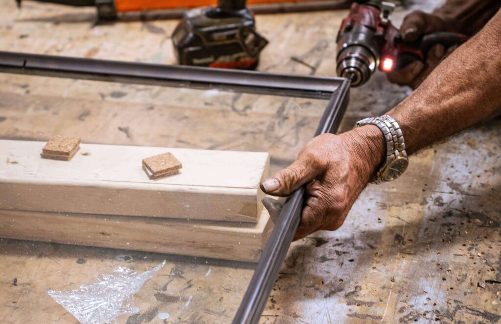 Technician securing a glass panel into a bronze window frame
